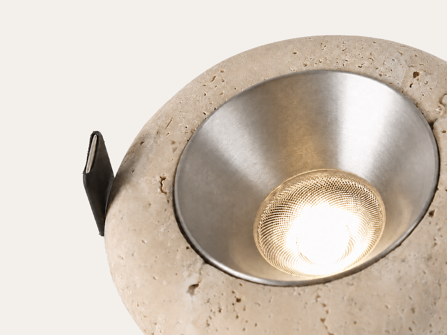 Close-up of natural travertine trim, reflector and COB LED optic