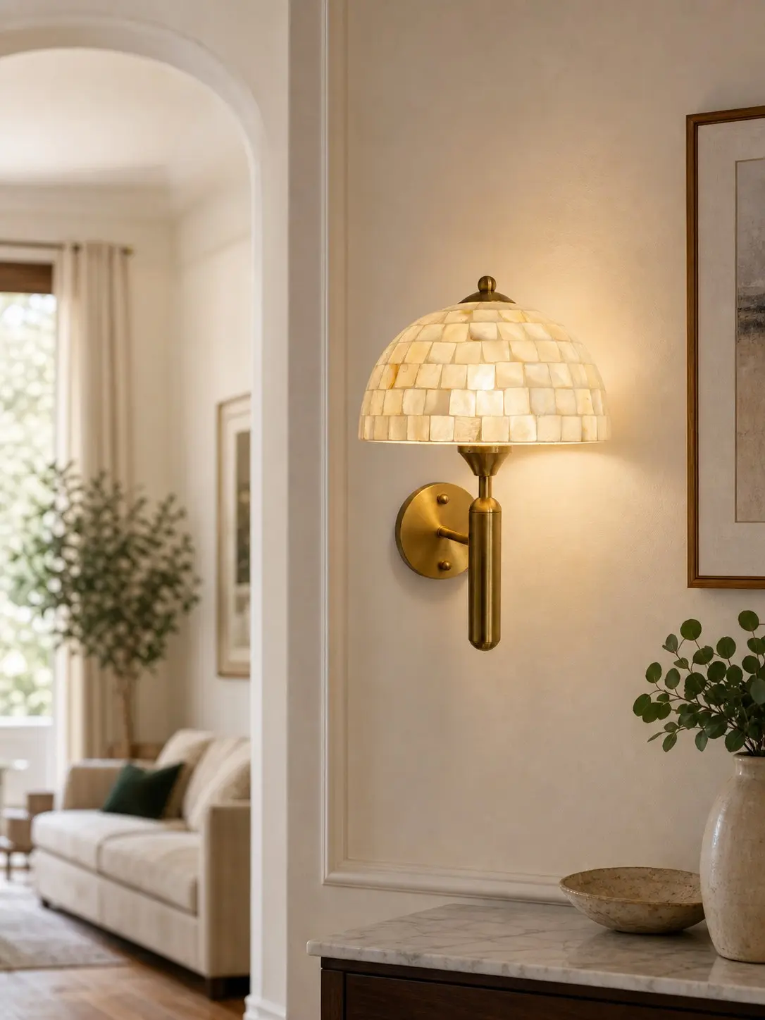 Lit antique brass mother of pearl wall sconce in an entryway